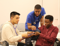 medical students teaching pre-med students how to take vitals.